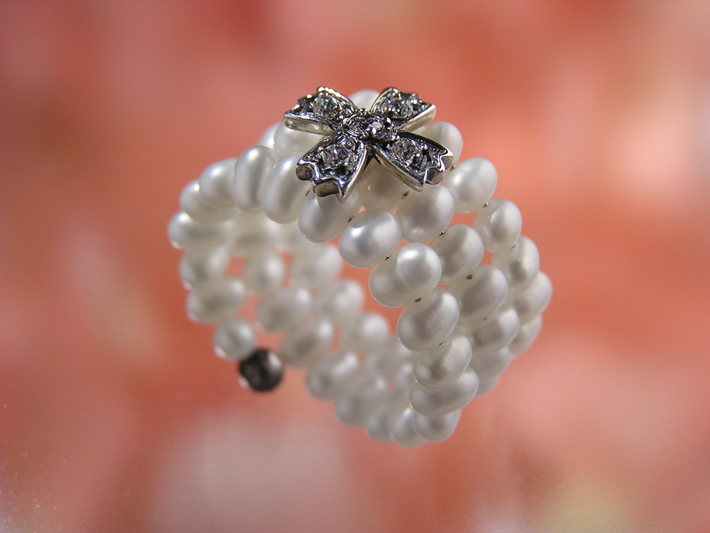 Une bague de perles blanches avec un ornement en forme de ruban